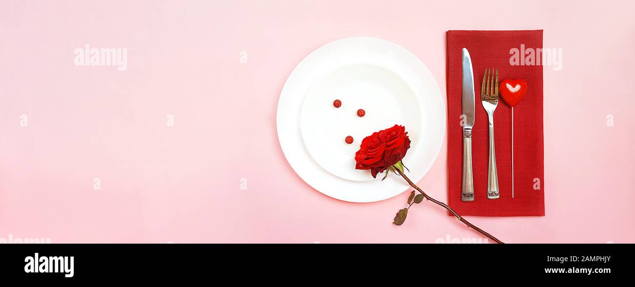 Romantisch gedeckten Tisch für Valentines Tag oder Abendessen Datum Feier Hochzeit. Valentines Tag Konzept mit rote Rose Bud White Platten auf Pastell rosa Tischdecke Hintergrund. Flach, Ansicht von oben kopieren. Stockfoto
