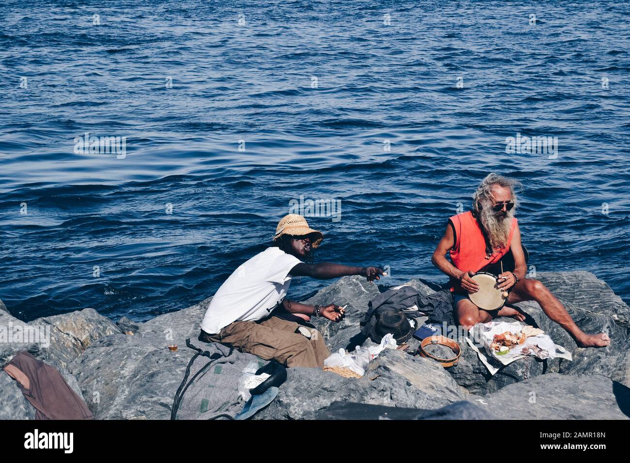 Zwei haarige Männer, die im Felsen neben dem essen Meer Stockfoto