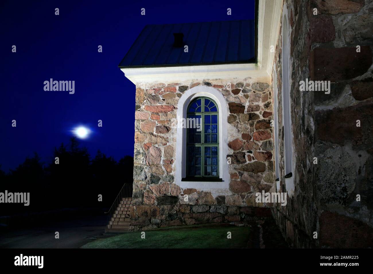 Beleuchtete Uskela-Kirche, entworfen von dem finnischen Architekten C. L. Engel und erbaut im Jahre 1832, bei Einbruch der Dunkelheit mit dem aufsteigenden Dunstigen Vollmond. Salo, Finnland. Januar 2020 Stockfoto