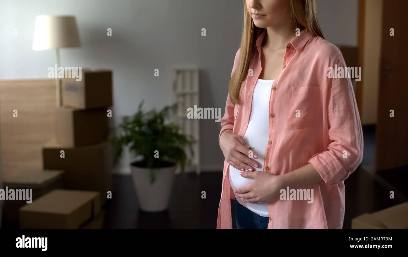 Betrübende schwangere Frau, die Kästen mit Dingen betrachtet, Ehemann verlässt die Familie Stockfoto