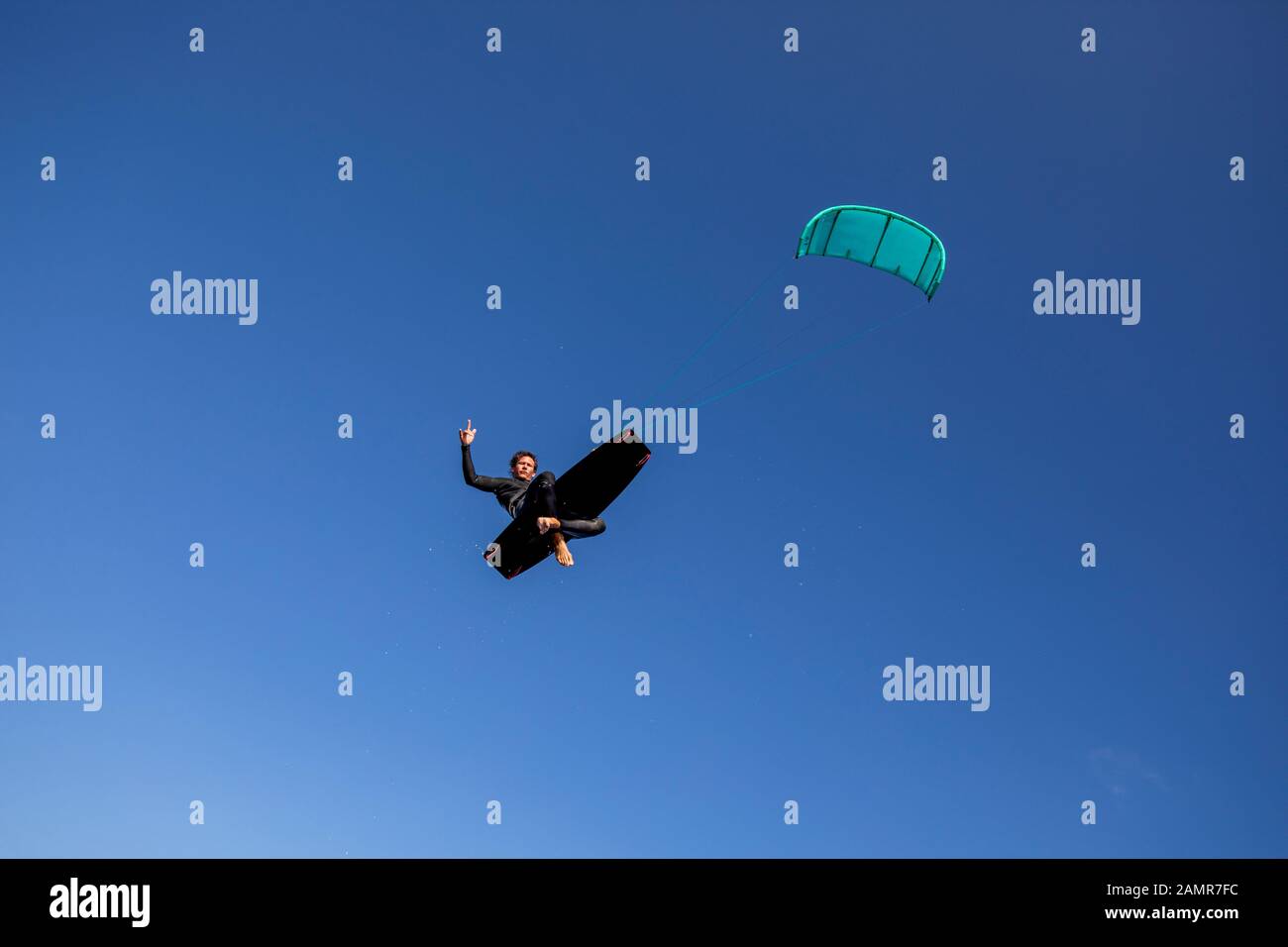 Kite Surfer rodeo Stil auf seinem Brett in der Luft mit der Hand Geste in die Luft. Stockfoto