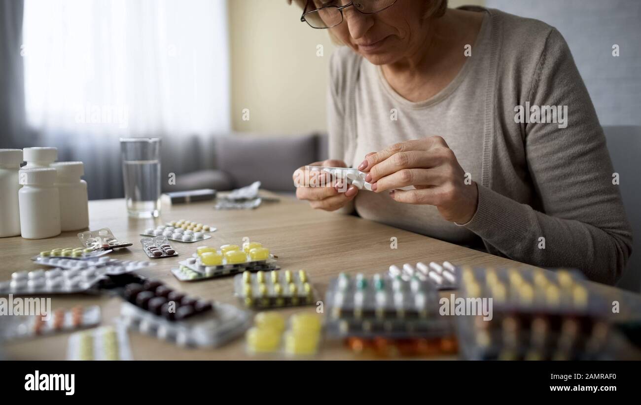 Alte Frau besessen von der Trinkpille im Gesundheitswesen, Überdosis, Selbstmedikation Stockfoto