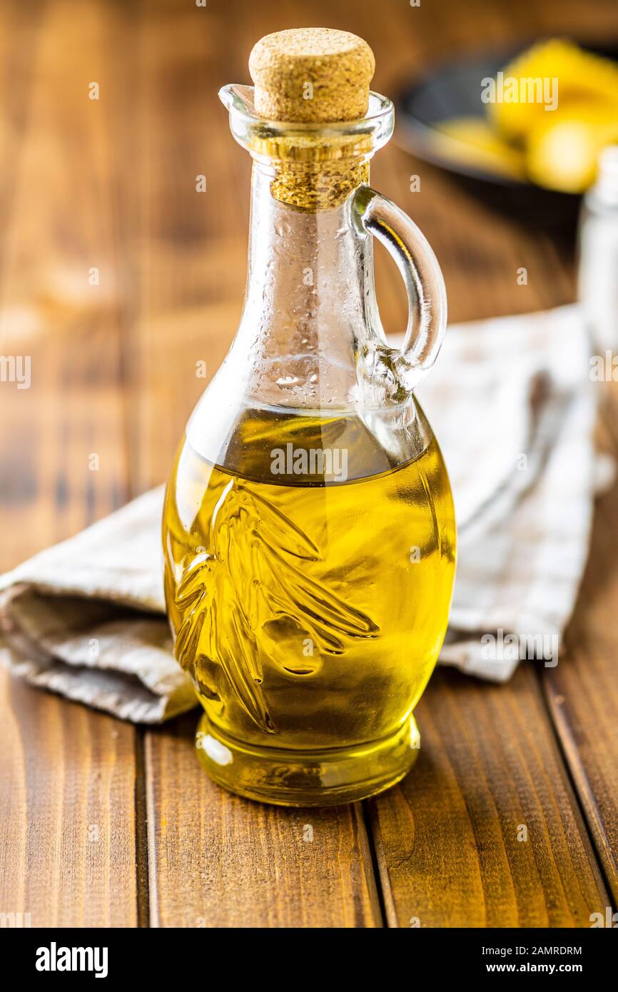 Olivenöl in Glasflasche auf Holztisch. Stockfoto
