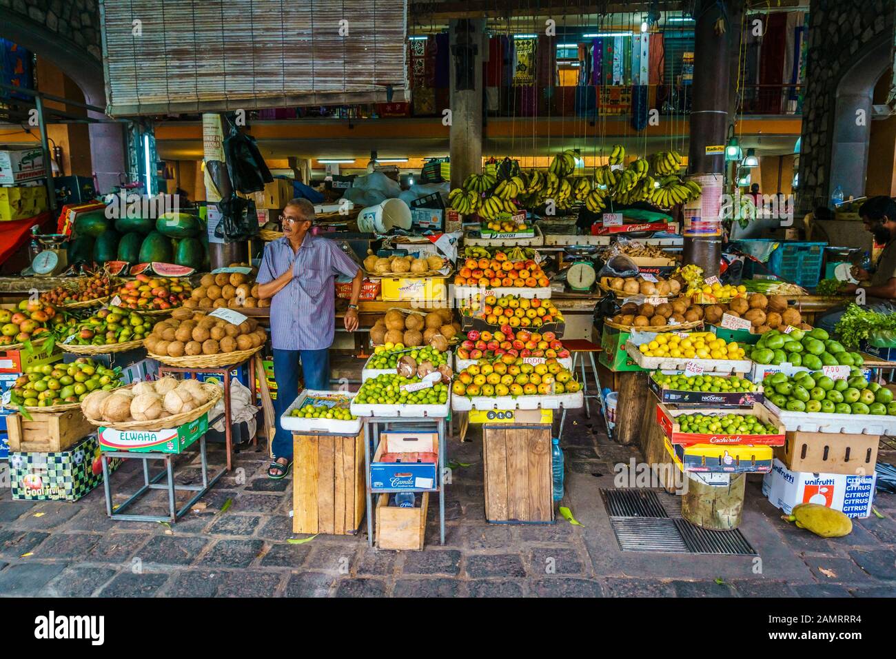 Central Market, Port-Louis, Mauritius, Dezember 2015 - EIN Verkäufer wartet geduldig auf Kunden an einem Stand von Obst und Gemüse Stockfoto