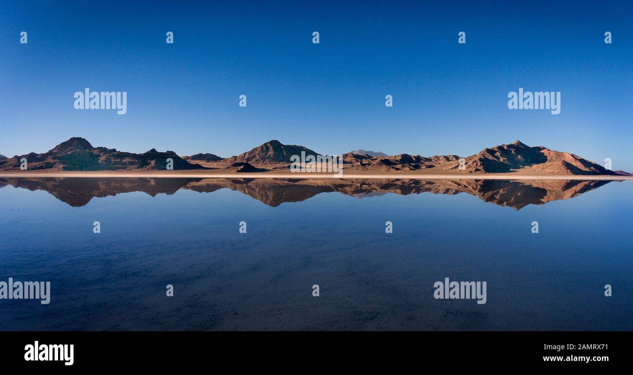 Reifenspuren sind sichtbar und Berge reflektieren auf einer dünnen Wasserschicht, die die Bonneville Salt Flats im Winter nahe dem Bonneville Speedway bedeckt. Stockfoto