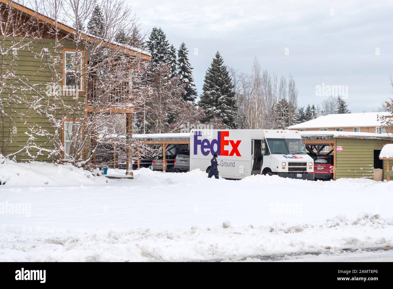 Ein FedEx Fahrer läuft durch starken Schnee zu ihrem LKW, nachdem er im Winter Pakete in eine Wohnung geliefert hat. Stockfoto