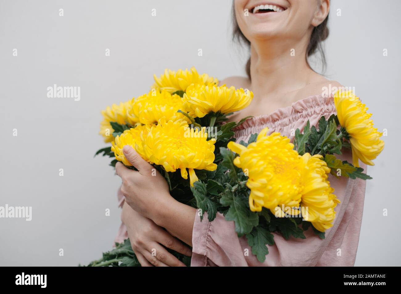Lächelnde Frau, die einen Blumenstrauß gelber Chrysanthemen hält Stockfoto