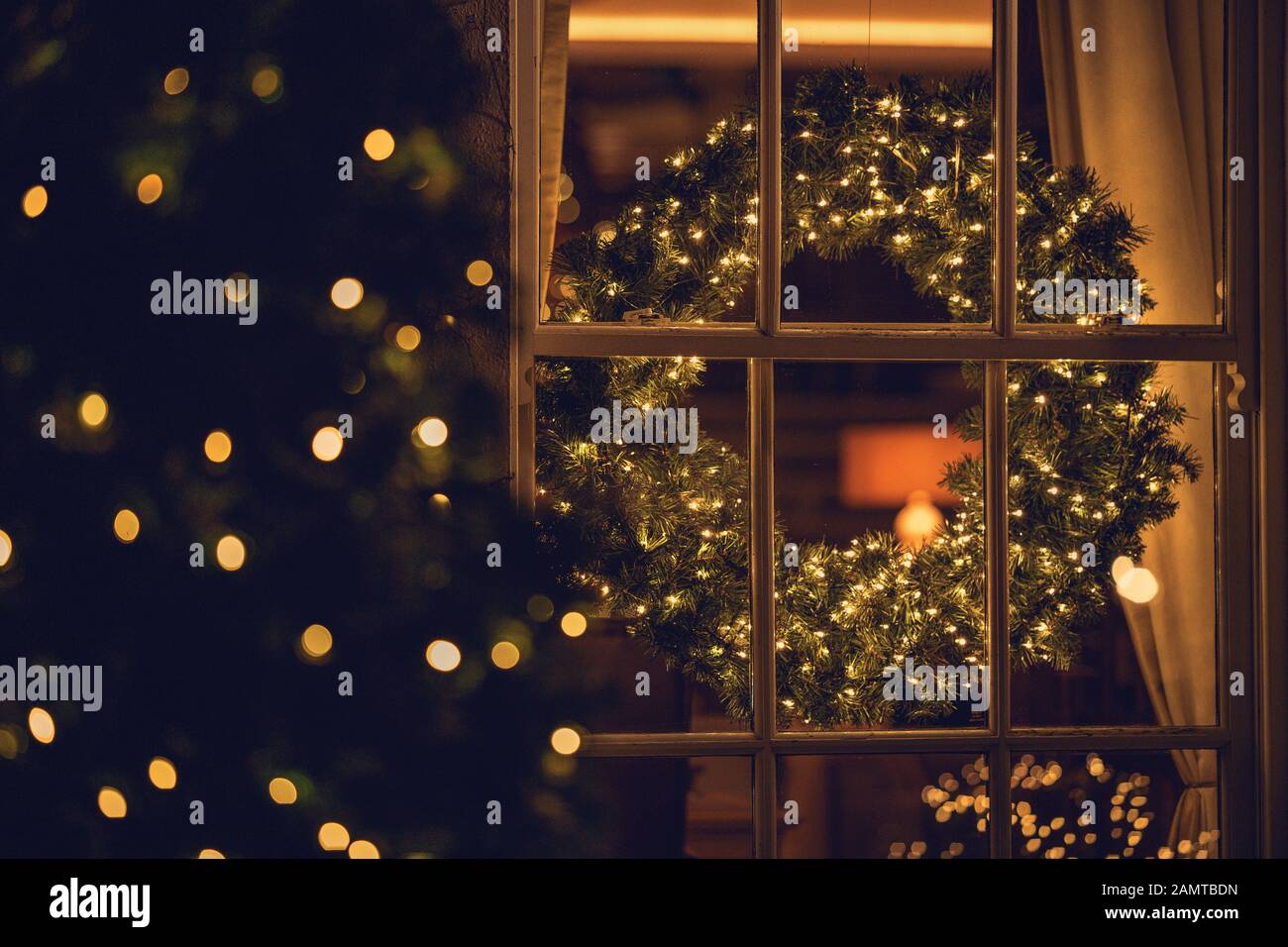 Blick durch ein Fenster eines Weihnachtskranzes im Wohnzimmer Stockfoto