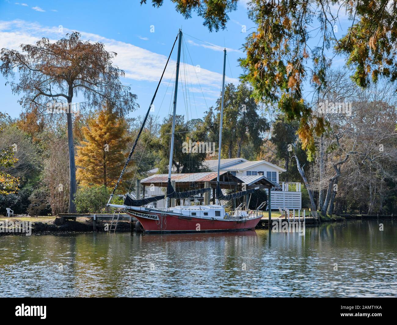 Rote Segelboot gebunden bis zu einem Dock auf das Magnolia Magnolia Springs Fluss in Alabama, USA. Stockfoto