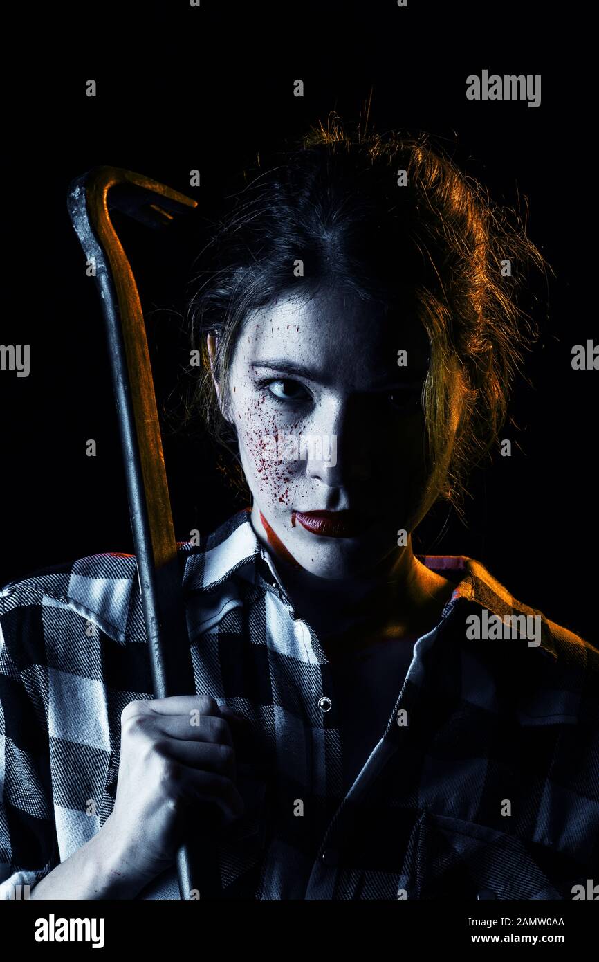 Blutiger ernst junge Frau mit Brecheisen in dunklen Blick auf Kamera getonten Bild Stockfoto