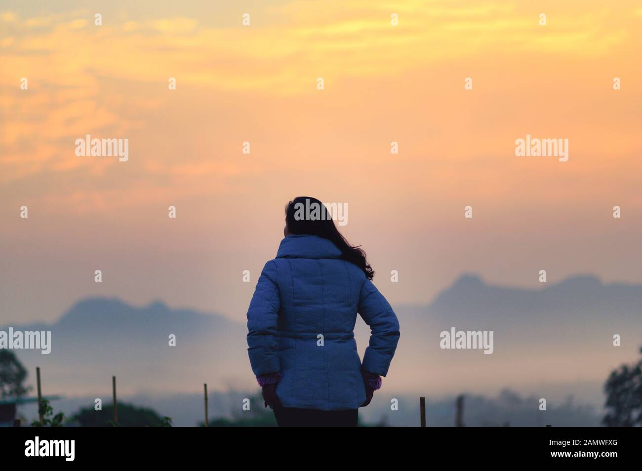 Eine junge Frau blickt auf den Sonnenaufgang über den Berg Stockfoto