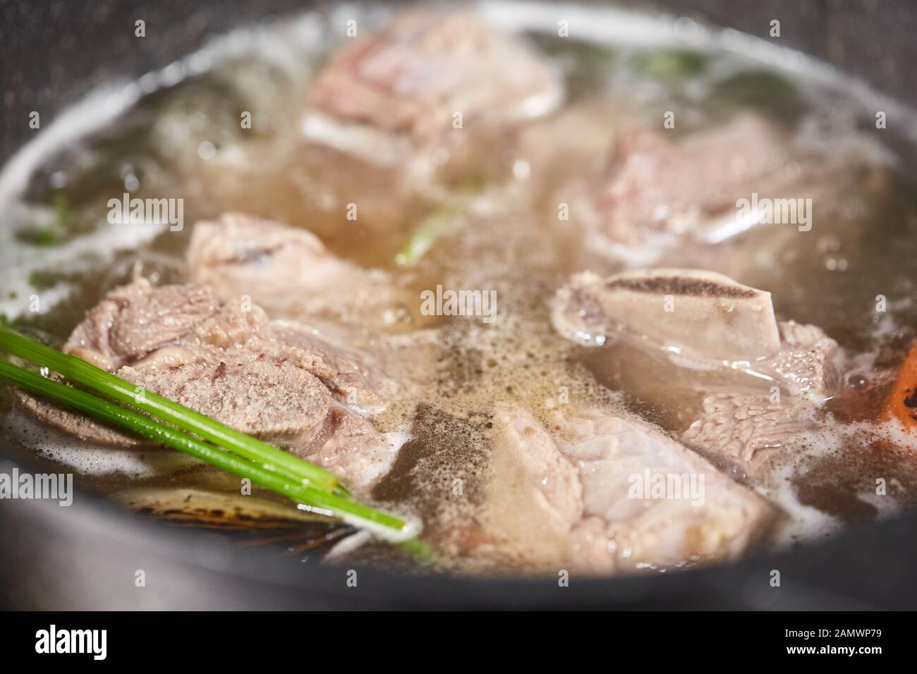 Traditionelle Rinderbrühe mit Gemüse, Knochen und Zutaten im Topf,  Kochrezept. Suppe in einem Kochtopf mit Pfanne auf dunklem Steingrund. Oben  Stockfotografie - Alamy