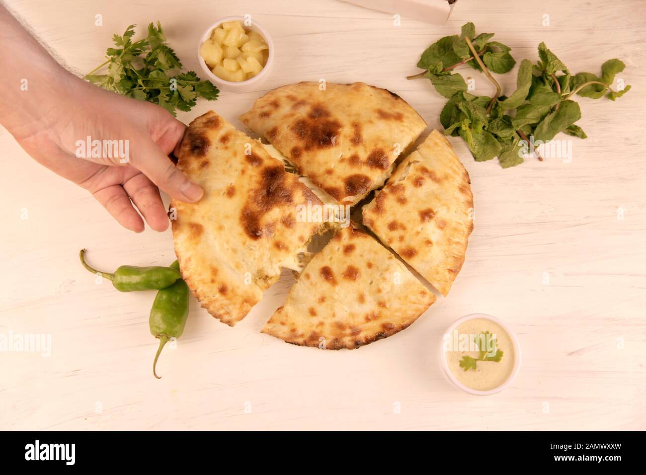 Hand ziehen Käse gefüllt Naan desi Pizza mit Kräuter Gemüse und Dips Stockfoto