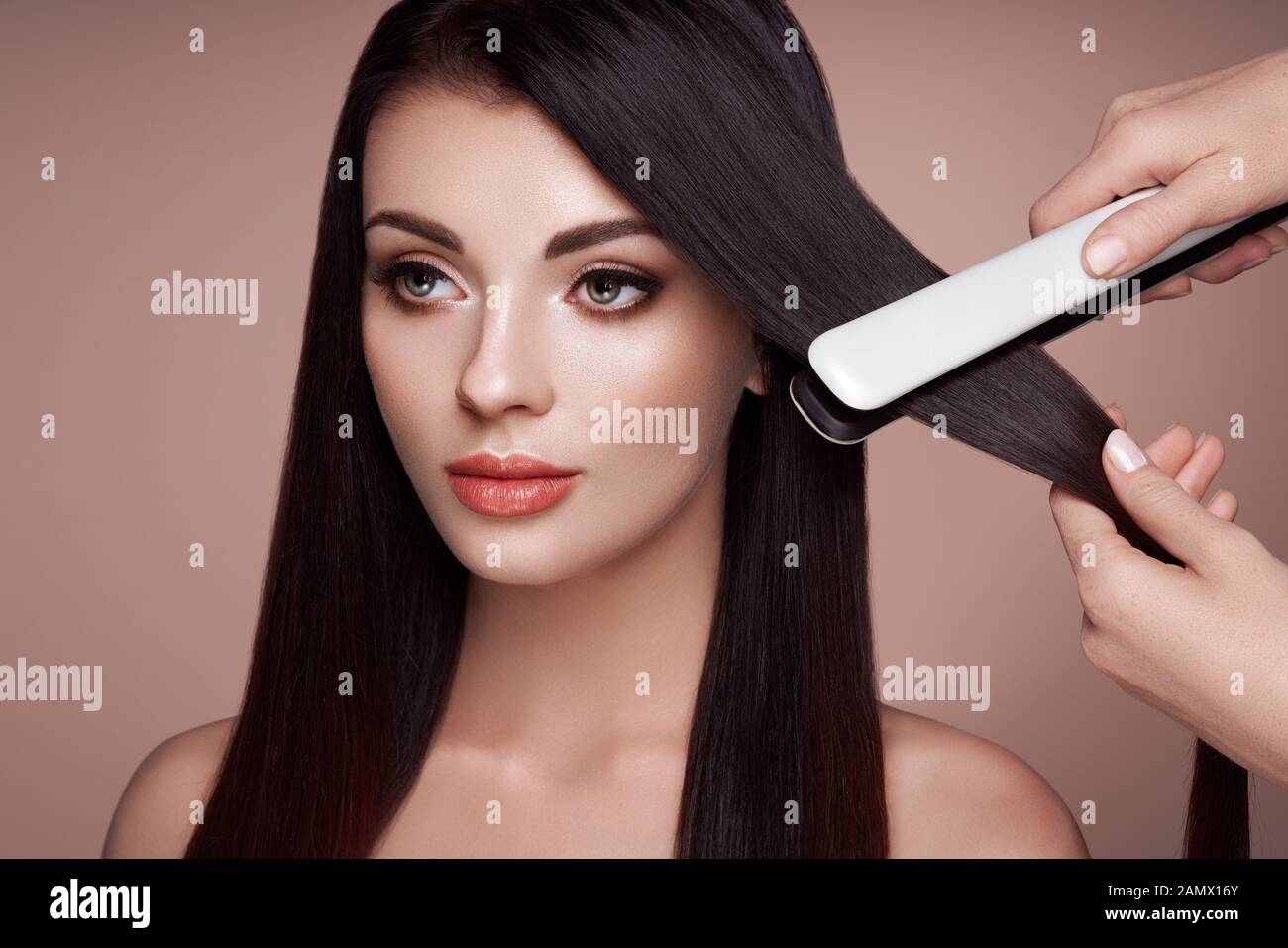 Friseur glätten lange dunkle Haare mit Fön Bügeleisen. Schöne Frau mit langen, glatten Haaren. Glatte Frisur Stockfoto