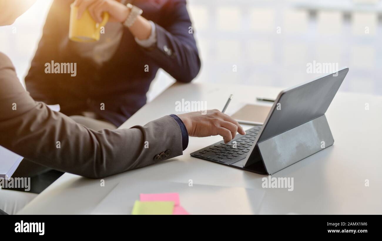 7/8 Schuß von zwei Unternehmer Beratung über ihre Arbeit mit digitalen Tablet in einfachen Arbeitsbereich Stockfoto