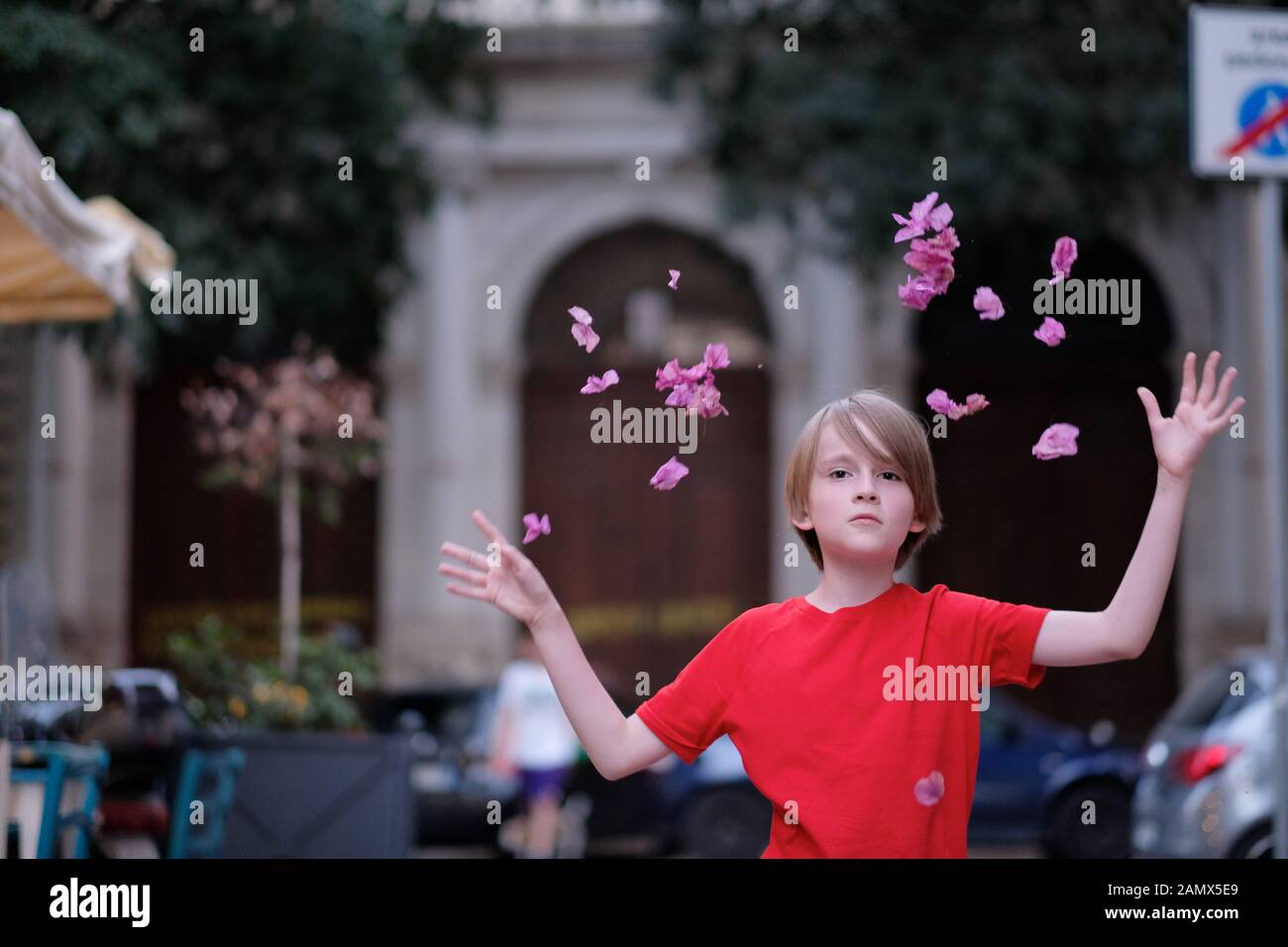 Das glückliche Gesicht des Kindes unter die herabfallenden Blüten von Blumen Stockfoto