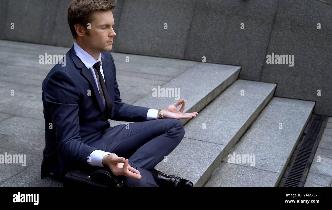 Mann in Business-Anzug sitzt in lotus-position und gewinnt Selbstkontrolle im Geschäft Stockfoto