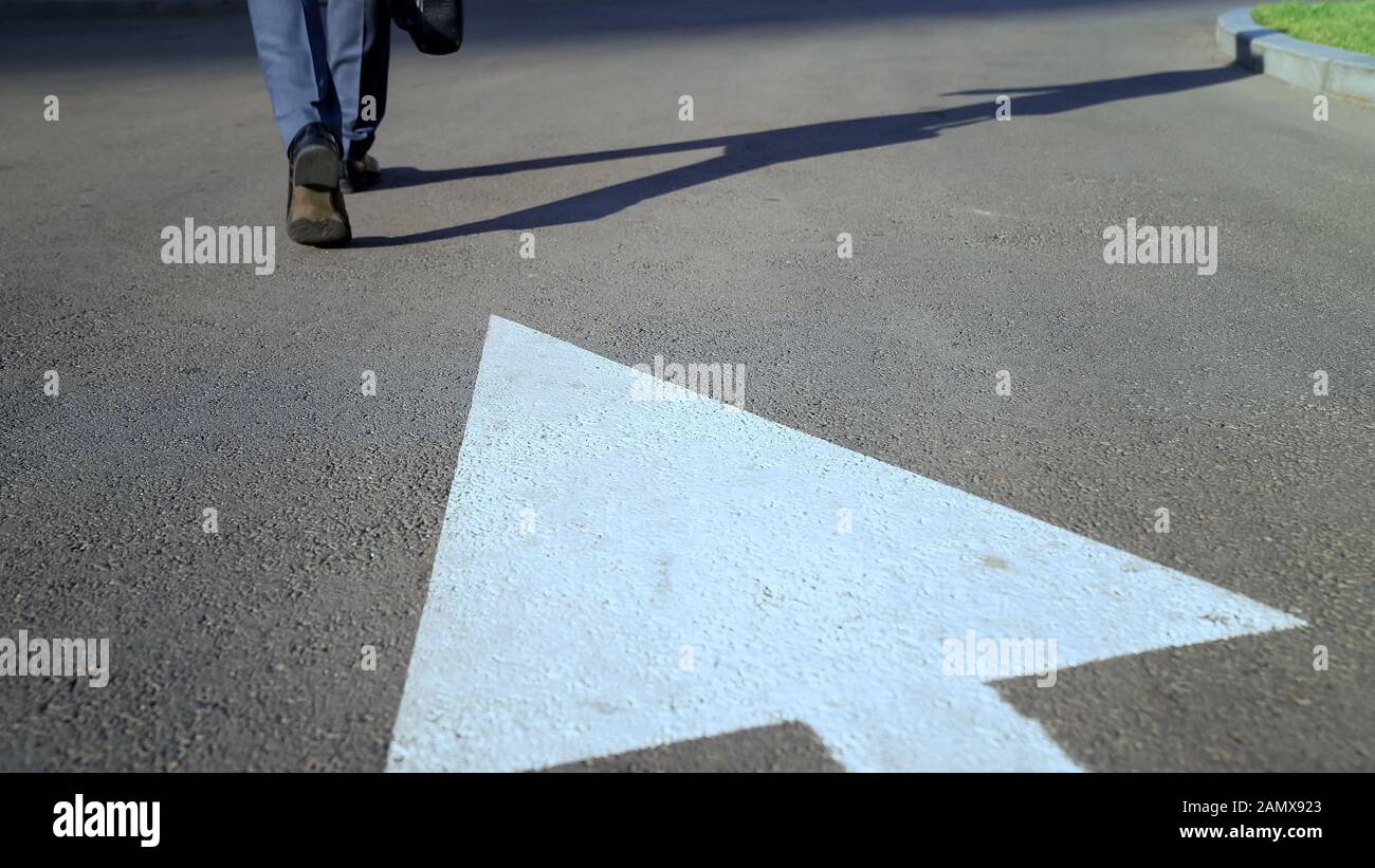 Mann, der auf einem weißen Pfeil spazieren geht, das Konzept, den richtigen Weg im Leben zu wählen, Karriere Stockfoto
