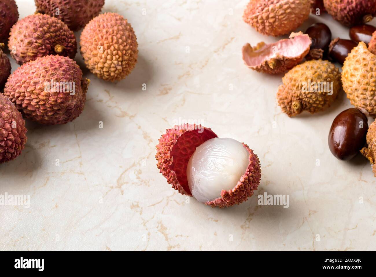 Ganze lychee, Schalen und Knochen in der Nähe von halb geschälten Litschi Obst (Litchi chinensis) auf einem weißen kithen Tabelle. Obst und Gemüse, vegetarisches Essen. Stockfoto