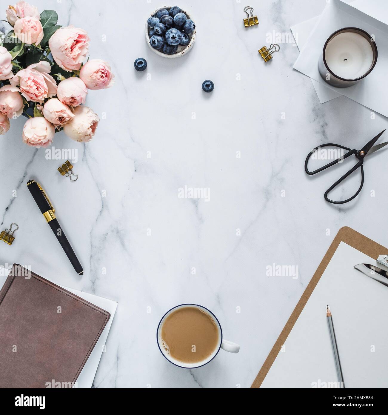 Blick von oben auf die weiblichen Home Office mit Kopie Platz im Zentrum. Zwischenablage, Blumen, duftende Kerze auf weißem Marmor. Feminine home office Mock up mit Kopie Platz für Text oder Design. Flach Stockfoto