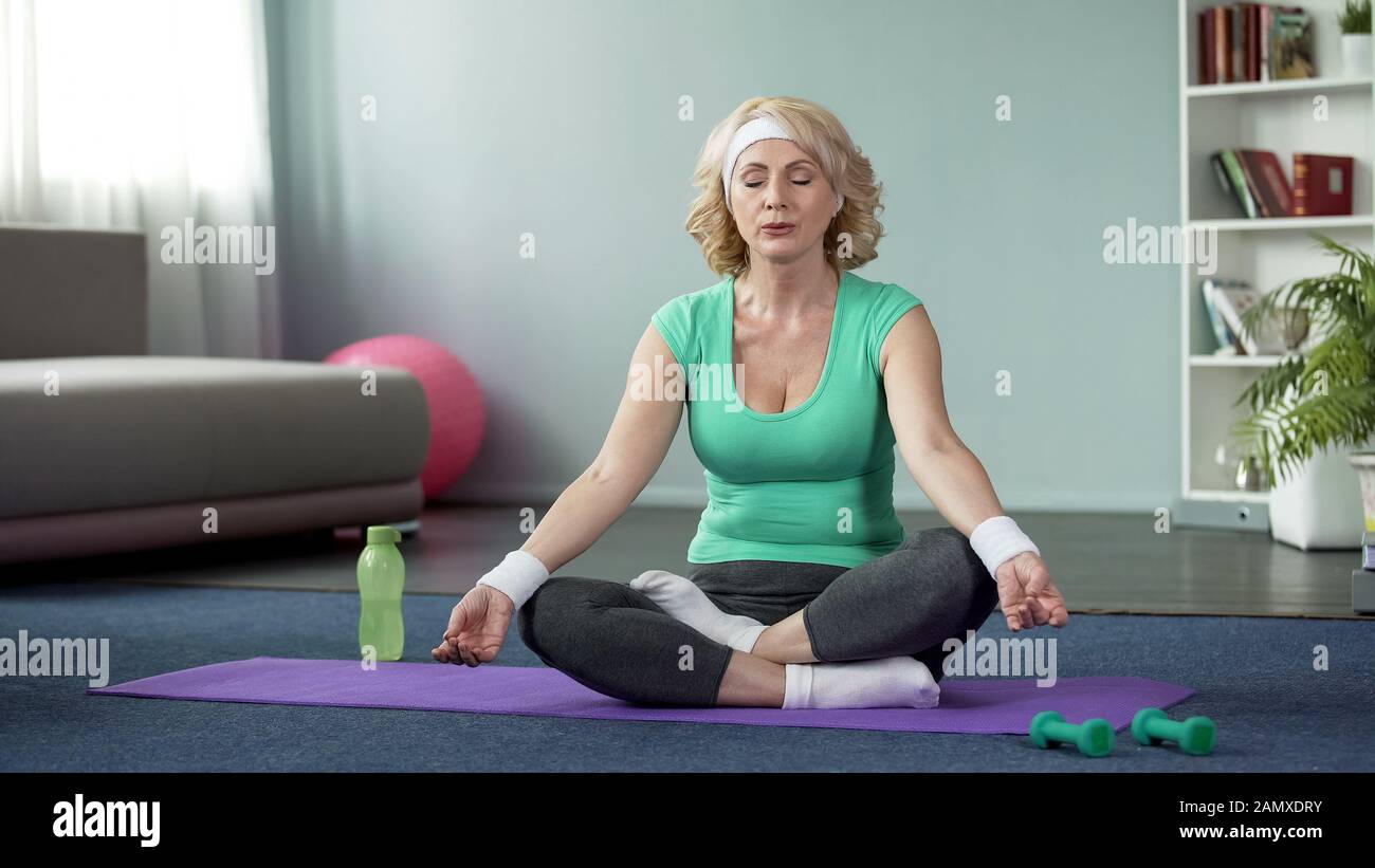 Reife Dame, die zu Hause Yoga praktiziert, Entspannungsübungen macht, Meditation Stockfoto