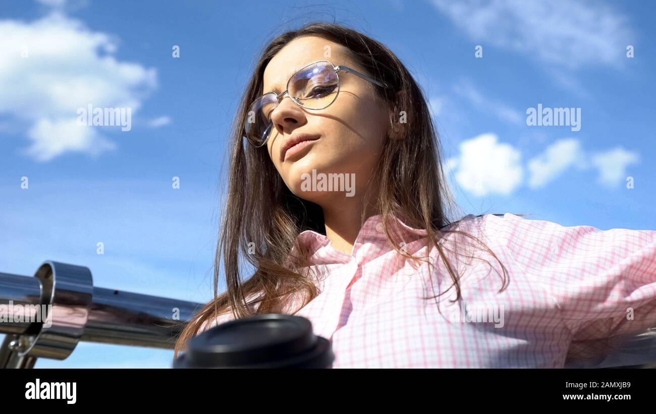 Verärgerte Dame mit Papierbecher, die über Lebensschwierigkeiten nachdenkt, entfliehen Sie der Realität Stockfoto