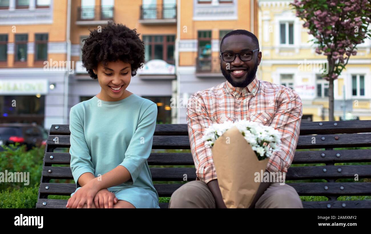 Peinlich versetzte Paare, die mit Blumen auf der Bank sitzen, erstes Datum, Zuneigung Emotionen Stockfoto