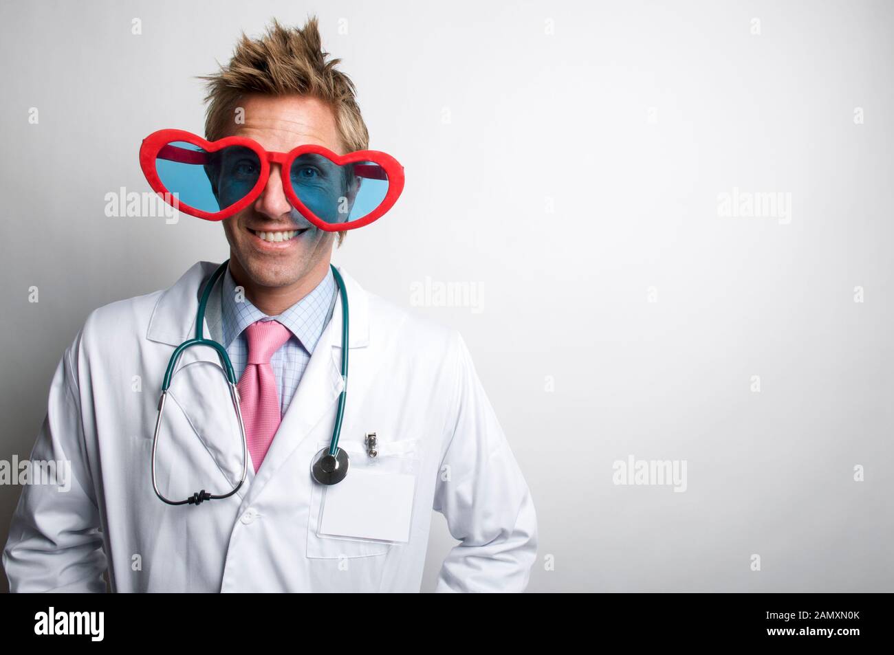 Liebe Arzt tragen weiße Kittel und Stethoskop hinter großen roten Herzen Lächeln - geformte Gläser Stockfoto