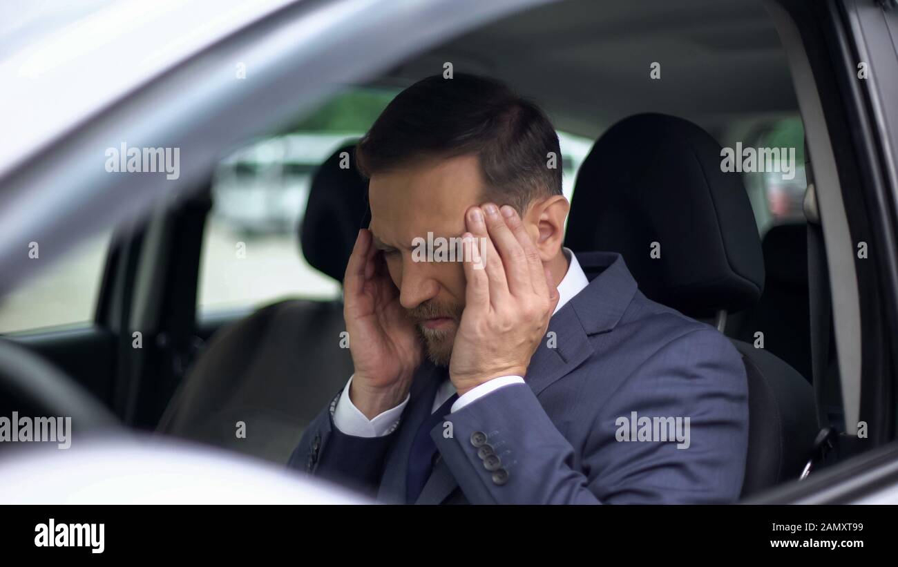 Gestresste Unternehmer spüren Kopfschmerzen im Auto, massieren Schlägel, Blutdruck Stockfoto