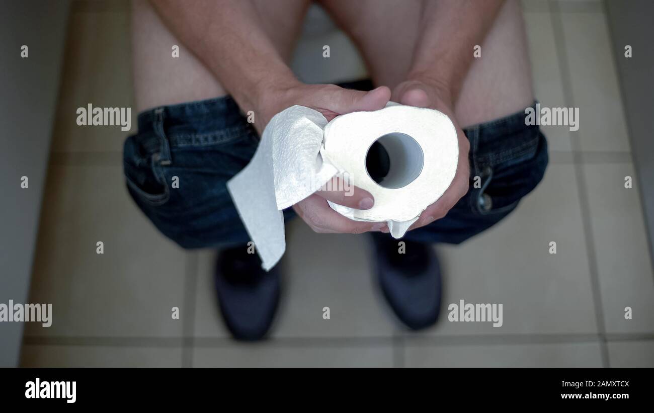 Mann, der Toilettenpapierrolle hält, blutende Schmerzen, Darmerkrankung, Gesundheit spürt Stockfoto