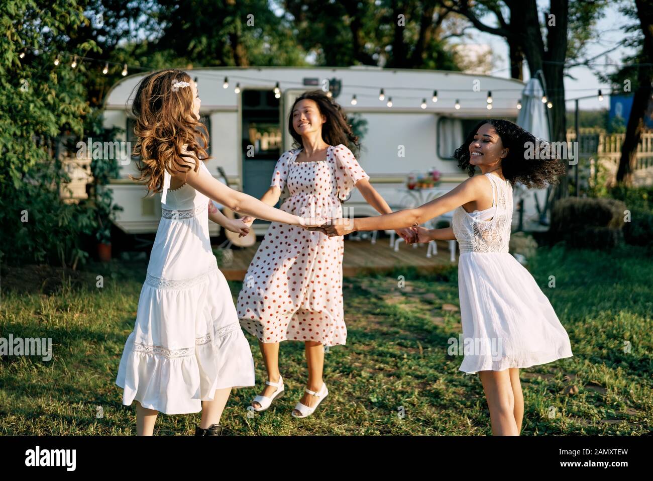 Gerne schöne Frauen tanzen im Freien auf Picknick. Multi-ethnische Mädchen haben gemeinsam Spaß im Sommer Reisen Urlaub genießen. Stockfoto