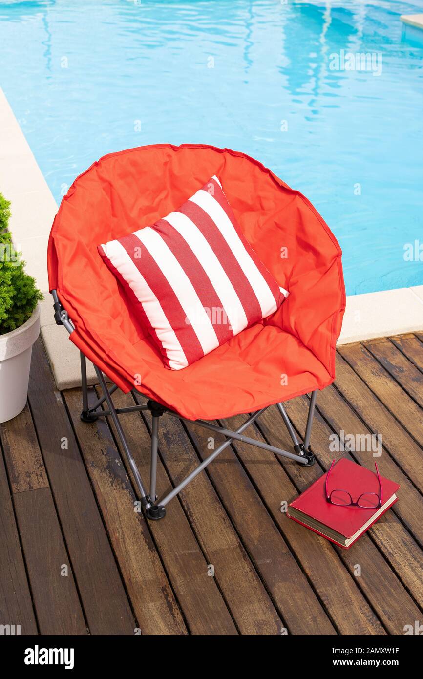 Sommerszene mit Schwimmbad, Stuhl, Getränk und Buch. Konzept für Urlaub oder Freizeit im Sommer. Kopierbereich Stockfoto