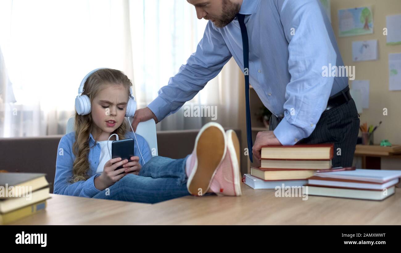 Alleinerziehender Vater, der versucht, mit der Tochter zu sprechen, Musik zu hören und ihn zu ignorieren Stockfoto