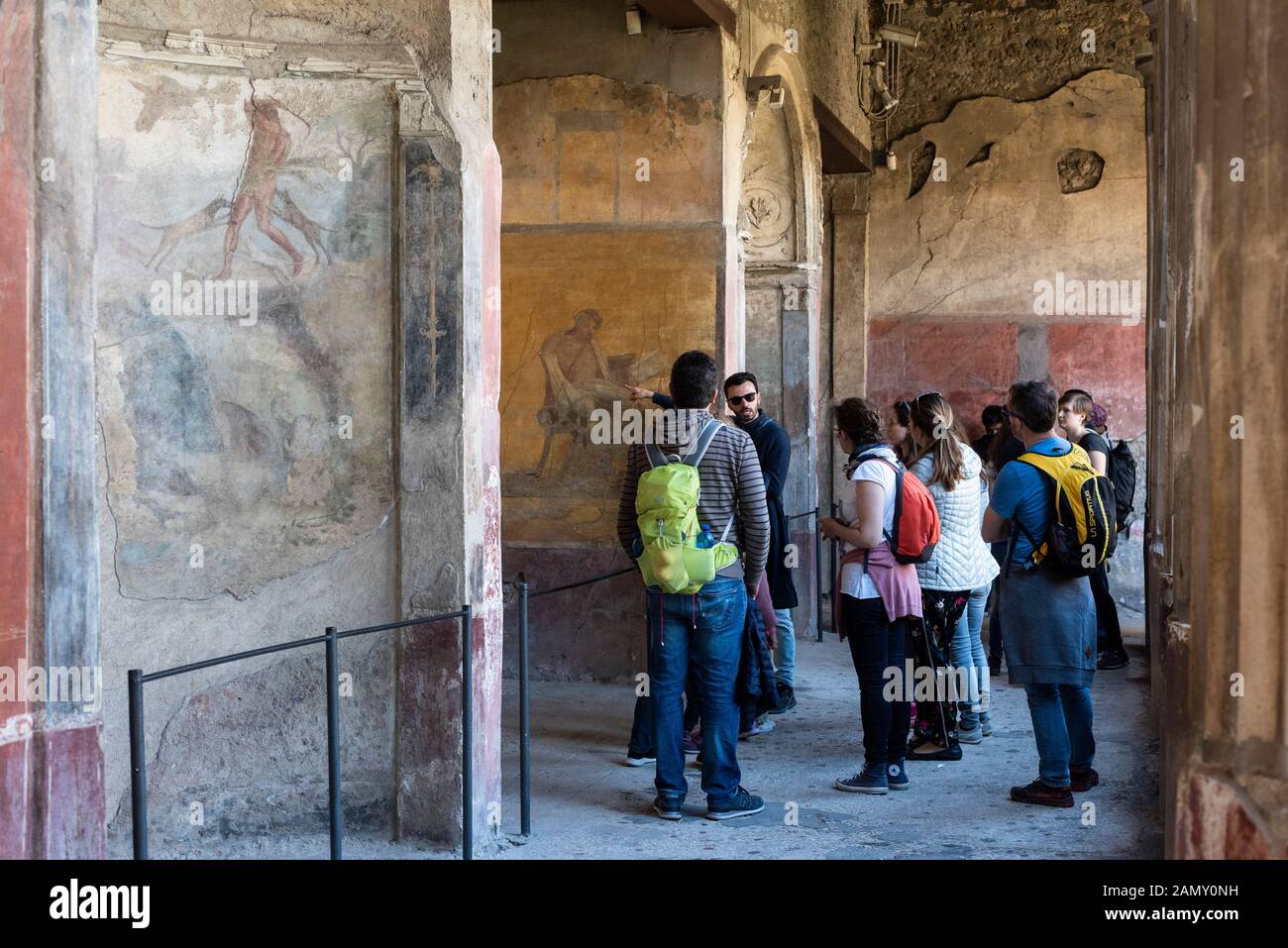 Pompei. Italien. Archäologische Stätte von Pompeji. Haus von Menander (Casa del Menandro). Eine Gruppe von Touristen, die die frescoierten Wände im hinteren Teil des betrachten Stockfoto