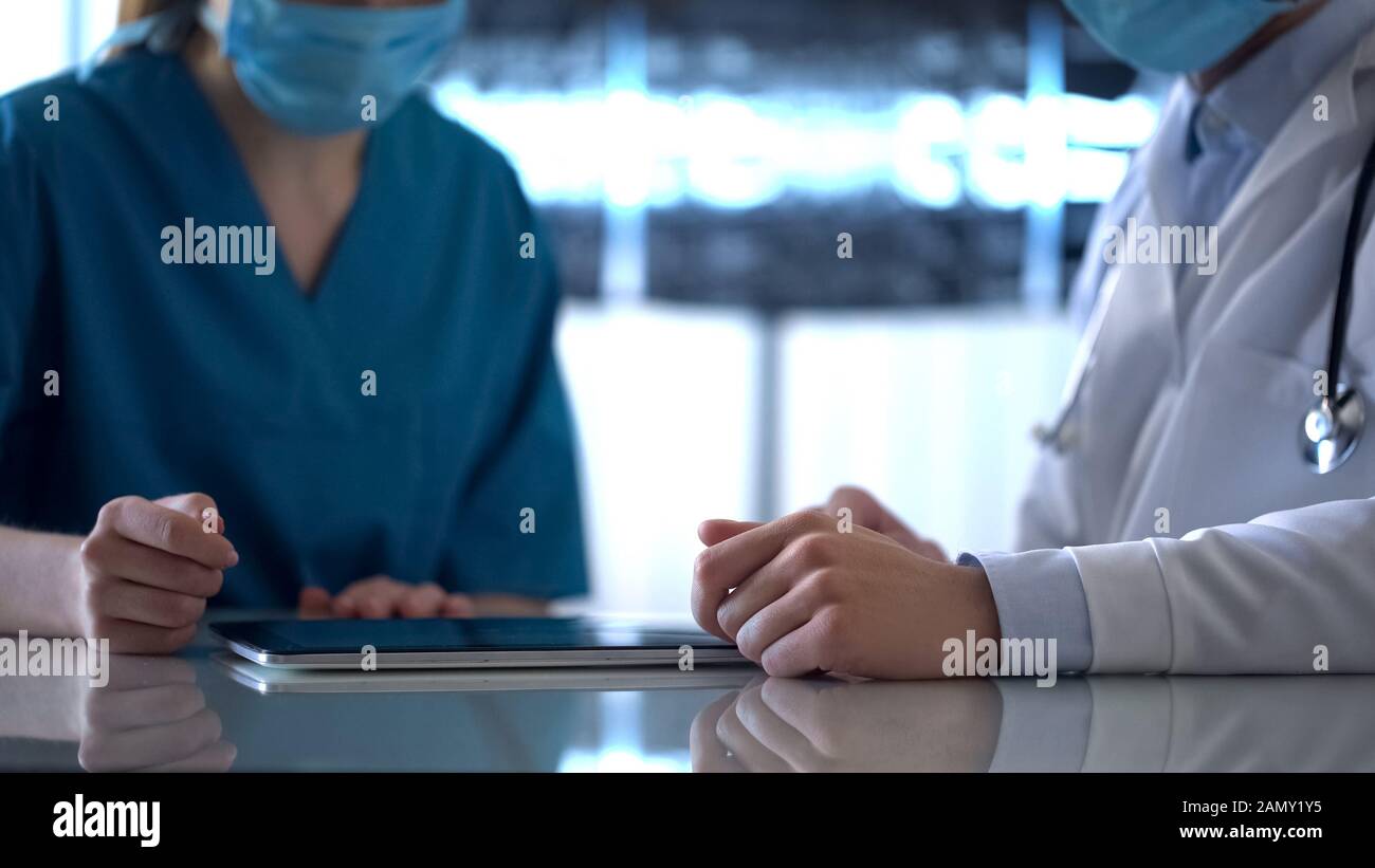 Zwei Ärzte überprüfen die Testergebnisse auf der Tablette und diskutieren die Diagnose des Patienten Stockfoto