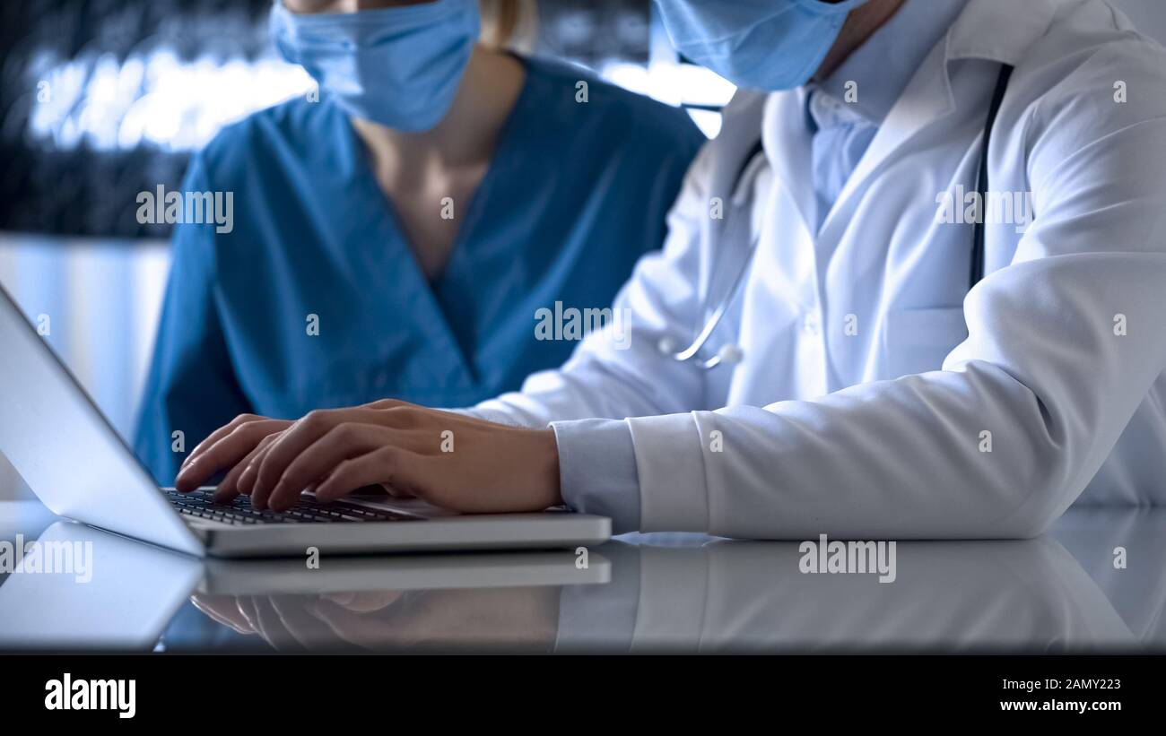 Ärzte, die Testergebnisse mit einem Laborlaptop online in medizinischen Aufzeichnungen ausfüllen Stockfoto
