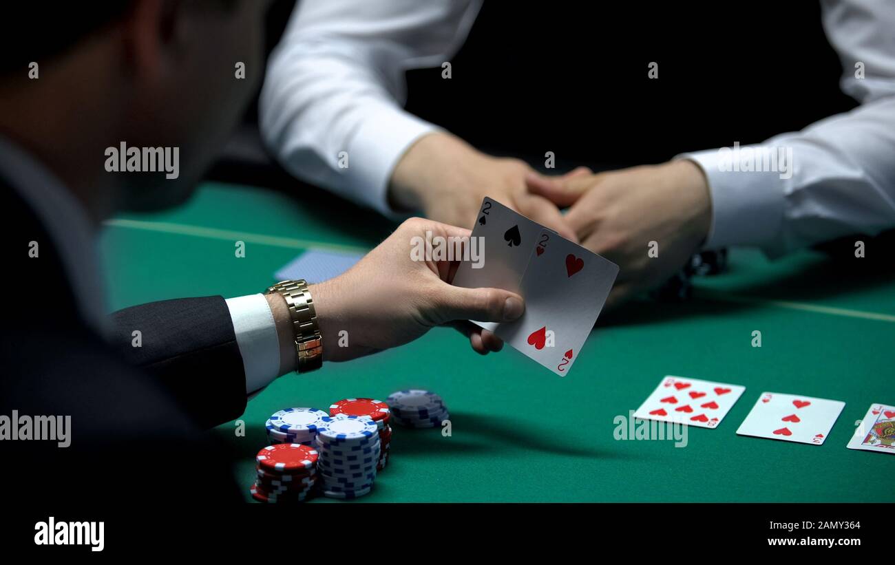 Ein Businessspieler, der auf eine schlechte Kombination von Croupier, einem Paar Deuces, blickt Stockfoto