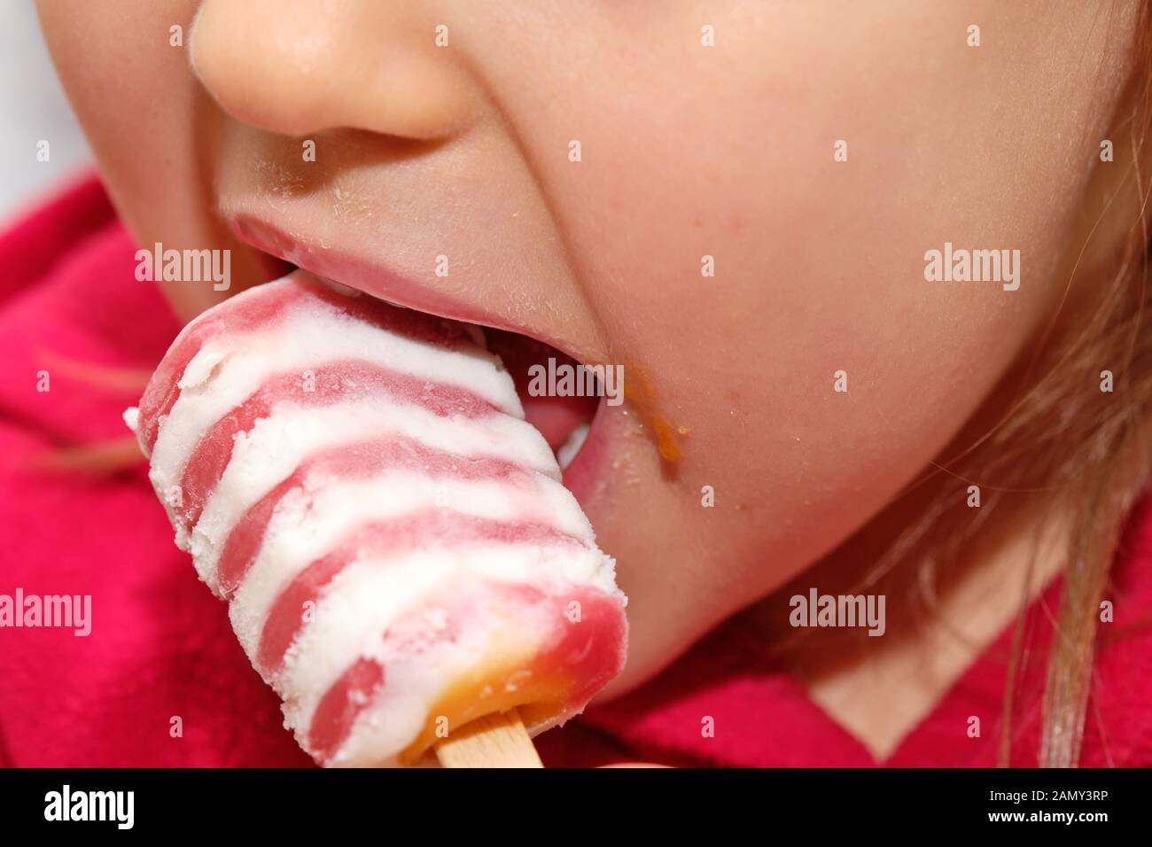 Nahaufnahme eines jungen kaukasischen Girl putting Eis in den Mund und isst es. Stockfoto