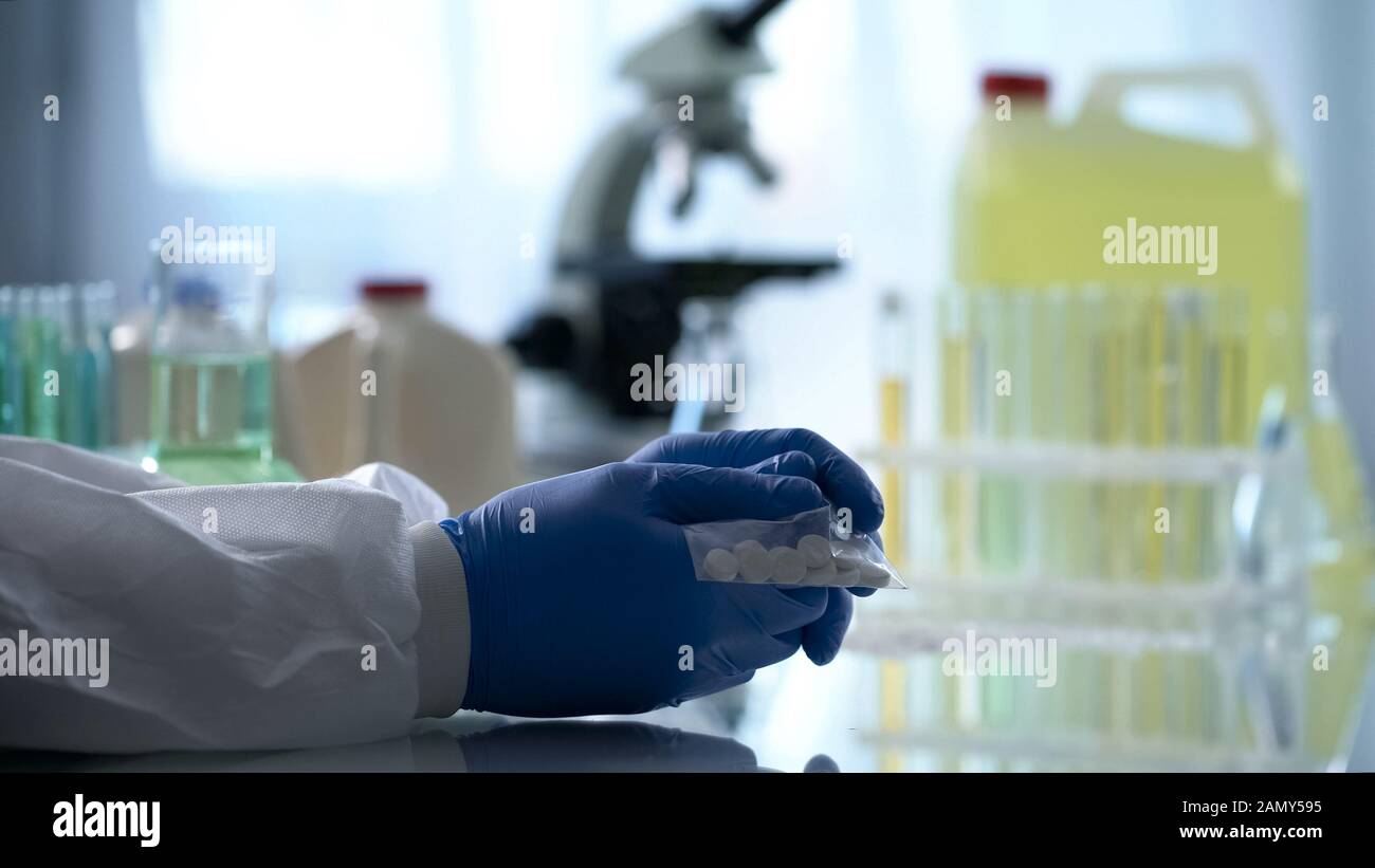 Labormitarbeiter, die Plastiktüten mit Pillen in heimlichen pharmazeutischen Labors halten Stockfoto