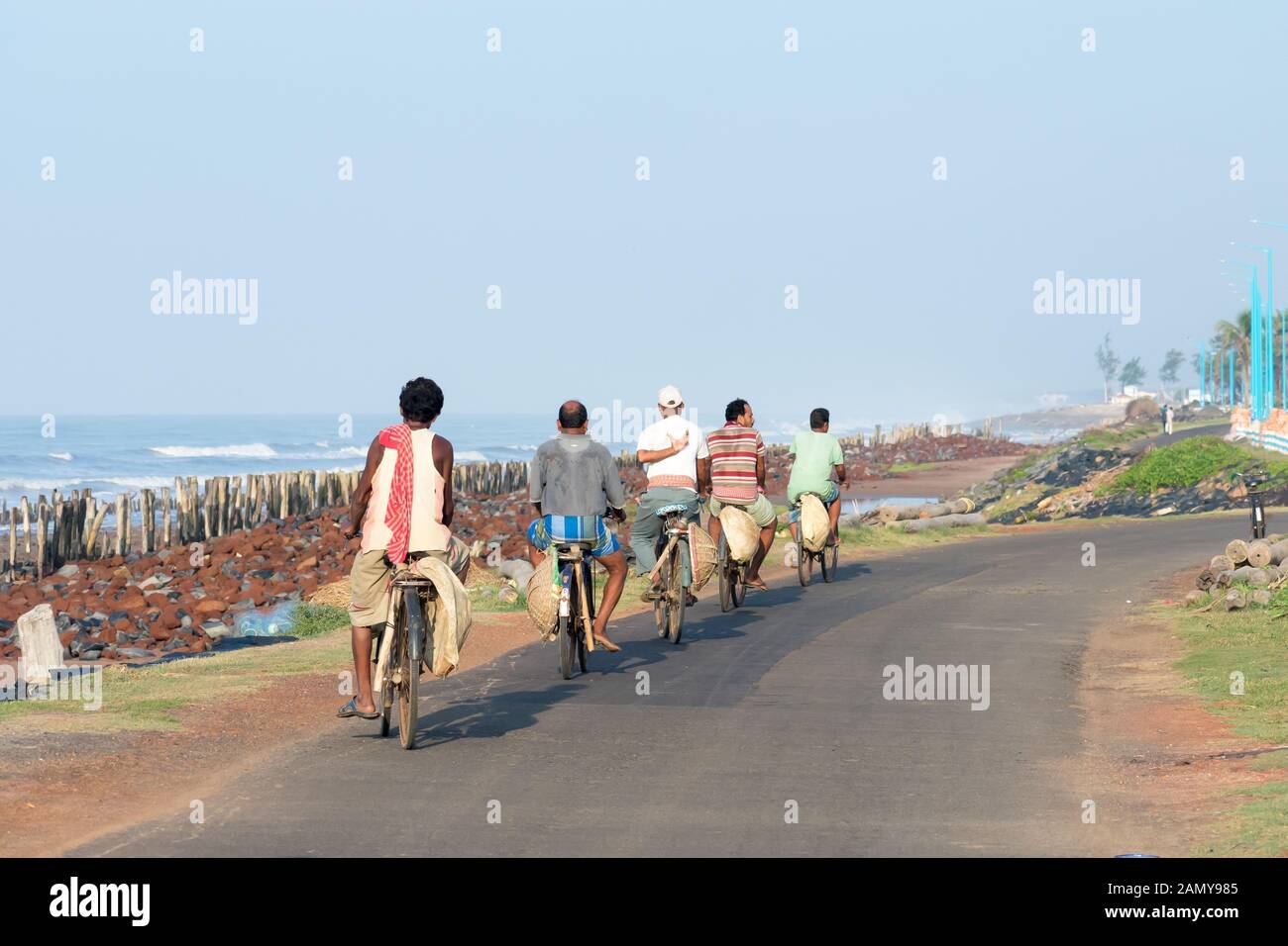 Kleine Gruppe von jungen und mittleren Alters Dorf Menschen in abgelegenen Küstenstreifen, auf dem Heimweg von der Arbeit in Fahrräder. Zyklus ist die primäre Modus der transpor Stockfoto