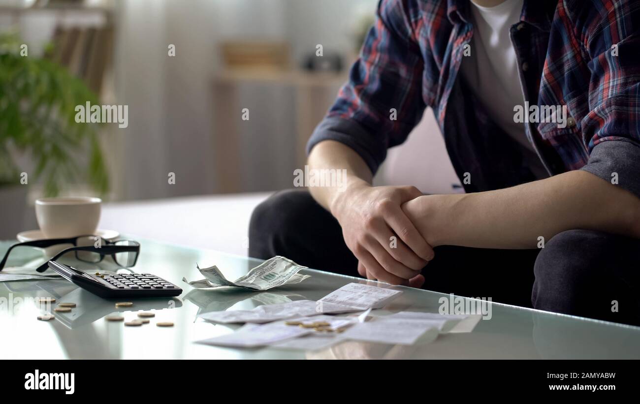 Junger Mann, der Hausfinanzierung rechnet, nur wenige Dollar und Cent für das nächste Gehalt übrig Stockfoto