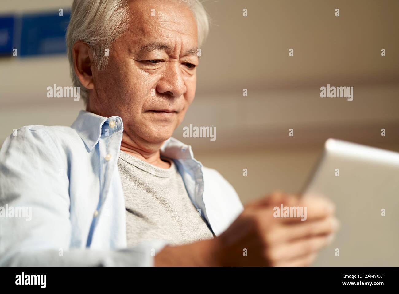 Asiatischer Senior mit Blick auf den Tablet-Computer Stockfoto