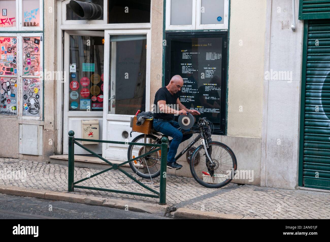 Ein Mann schärft mit Hilfe eines Radrads die Messer. Fotografiert in Lissabon, Portugal Stockfoto