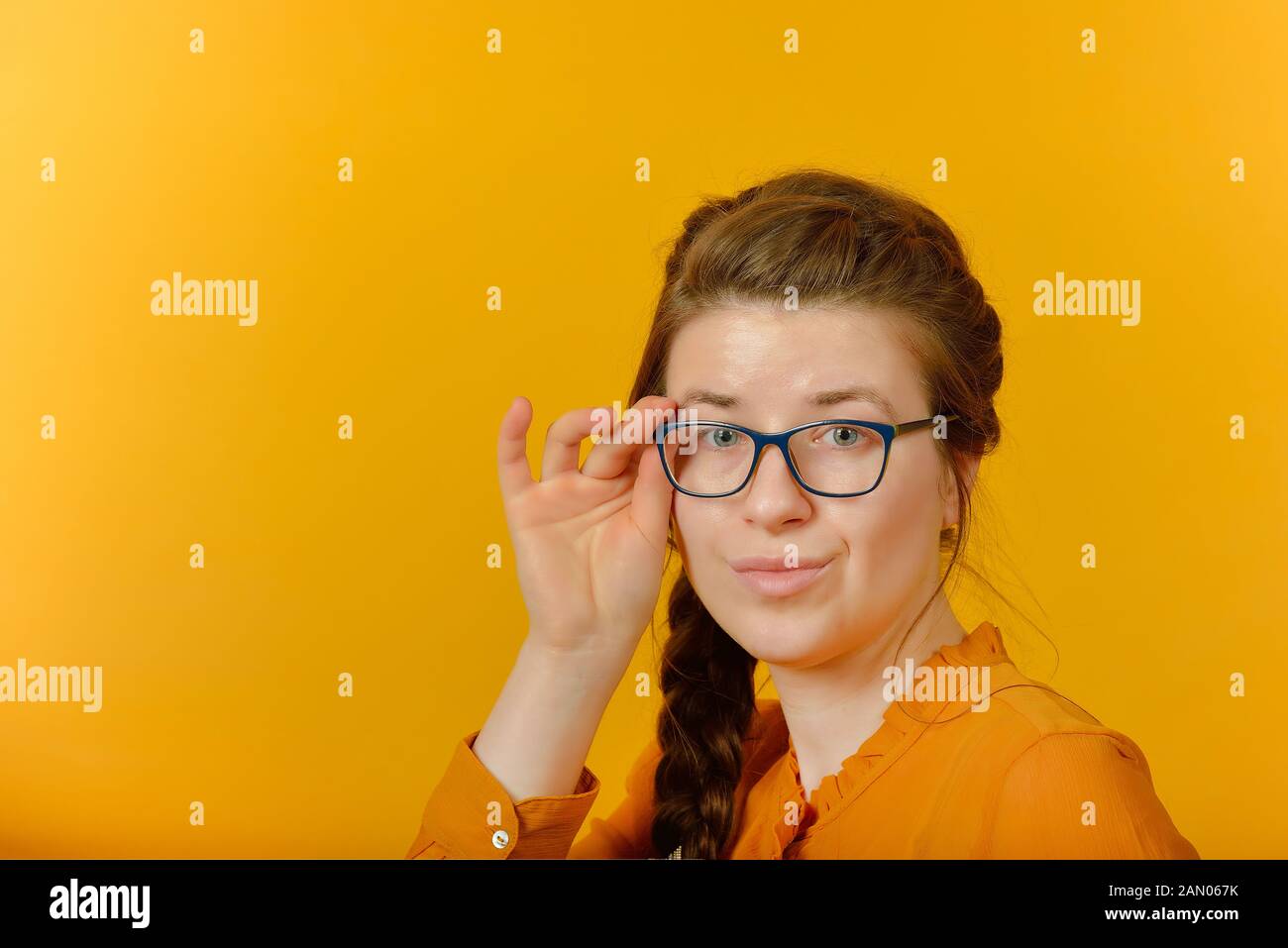 Mädchen mit Brille in die Kamera schaut auf gelbem Hintergrund. Stockfoto