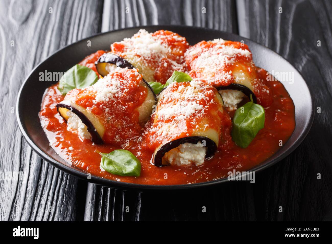 Appetithäppchen aus gefüllter Auberginen mit Ricotta-Käse in Tomatensauce in einem Teller auf dem Tisch. Horizontal Stockfoto