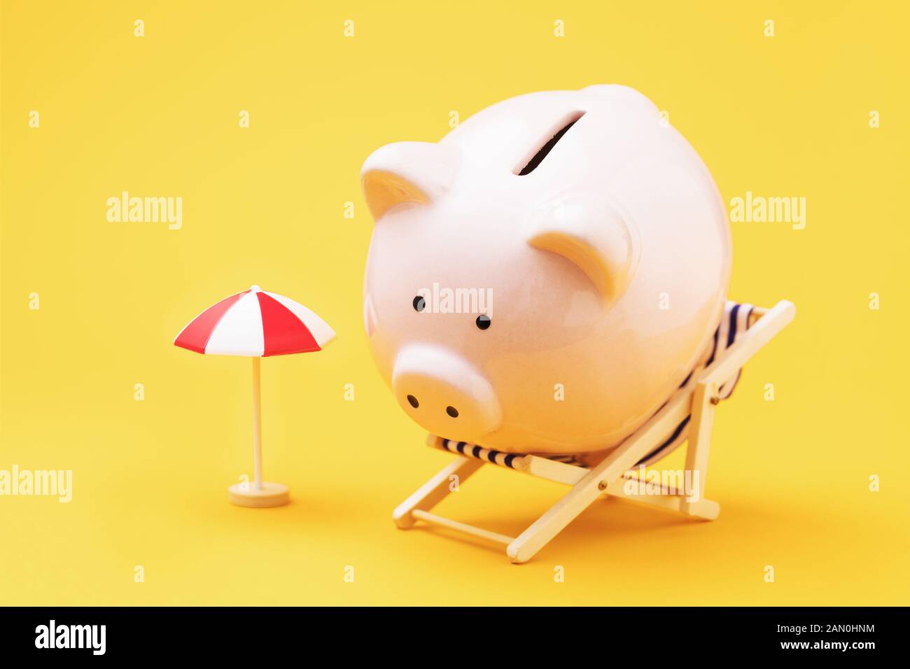 Sparschwein, Liegestuhl und Sonnenschirm auf gelbem Hintergrund. Konzept zur Anhäufung von Vermietungen Geld Stockfoto