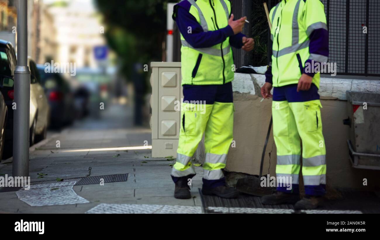 Zwei männliche Mitarbeiter des städtischen Dienstes rauchen in der Pause, wenig bezahlt Stockfoto