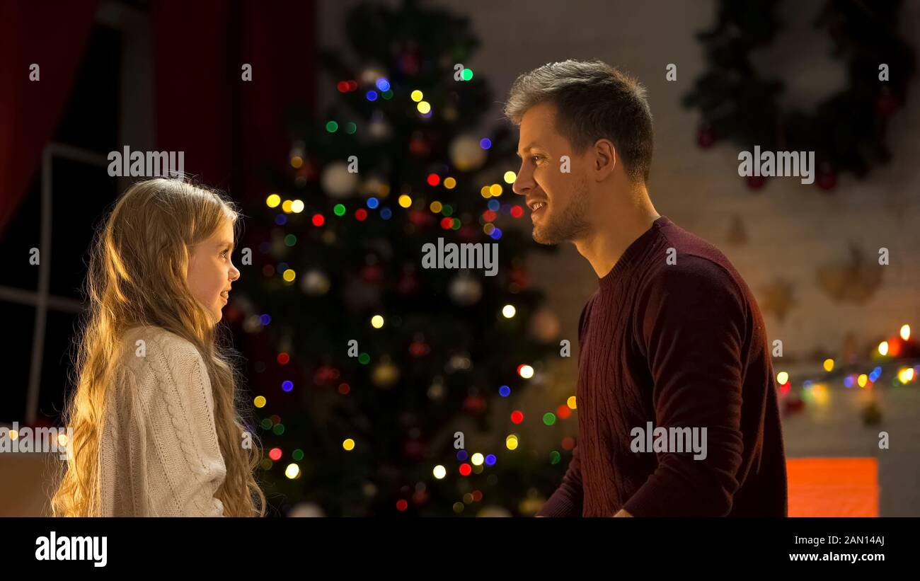 Vater und Tochter sitzen in der Nähe des Weihnachtsbaums und feiern gemeinsam Feiertage Stockfoto