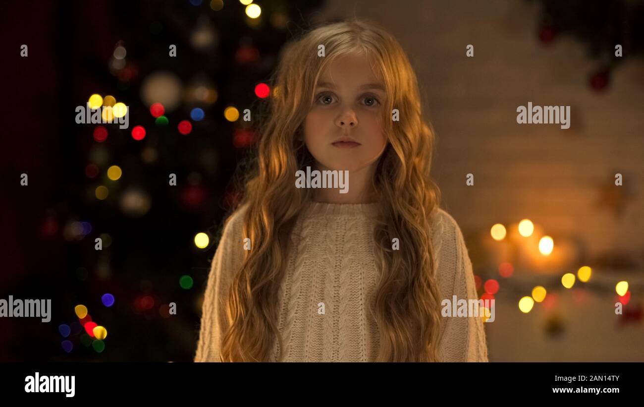 Trauriges verlassenes Mädchen, das nach einer Kamera sucht, die eine neue Familie im Waisenhaus wartet, Weihnachten Stockfoto