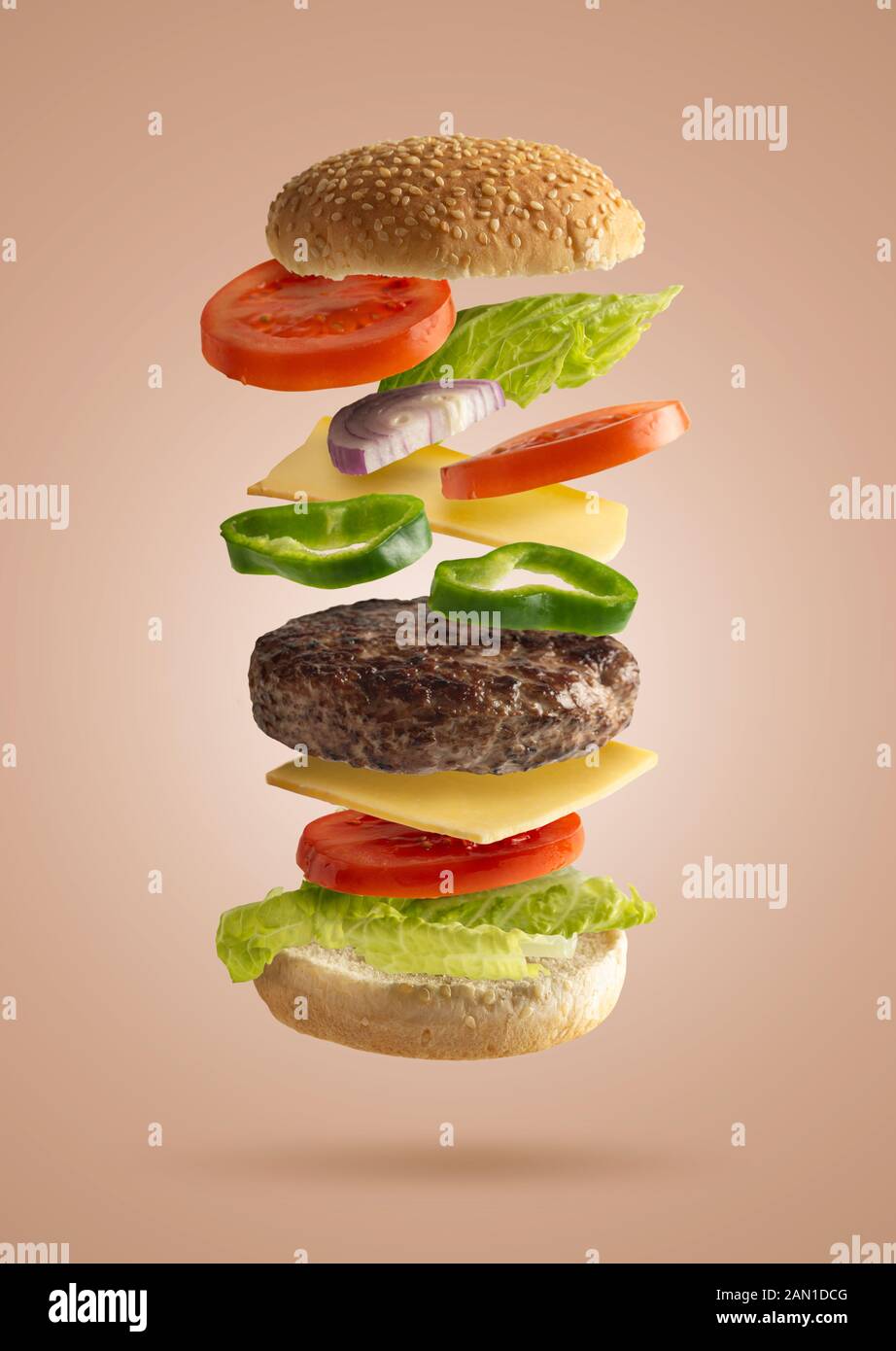 Hamburger sandwich Fliegen mit pflanzlichen Inhaltsstoffen, isoliert von den beigen Hintergrund, Salat, Zwiebeln, Tomaten, Käse, grüner Pfeffer Stockfoto